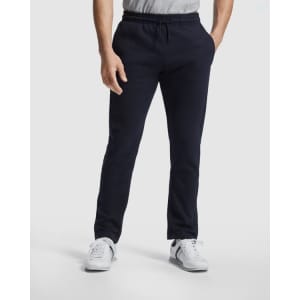 Track pants in navy blue, featuring a casual fit and an elastic waistband, worn with a grey top and white shoes.