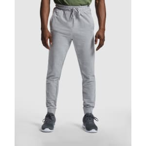 Grey track pants with an elastic waistband and side pockets, featuring an emblem on the hip.