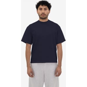 A navy short sleeve garment dye t-shirt displayed on a model, paired with grey shorts. The t-shirt features a logo.
