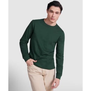 A green long-sleeved T-shirt displayed on a model, paired with light-coloured pants. The shirt features a logo.