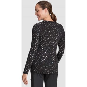 A woman models a black long-sleeve Tessa Tee featuring a scattered print of colourful dots. The tee has a fitted silhouette.