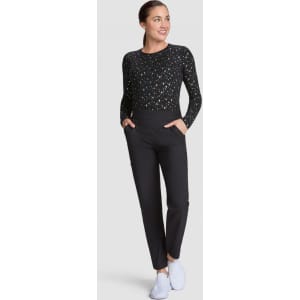 A black long-sleeve top with a patterned design, paired with black trousers and white shoes. The model stands with hands in pockets.
