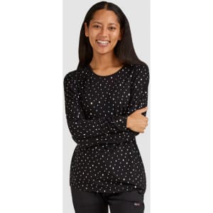 A long-sleeved black tee featuring a polka dot pattern in various colours, worn by a smiling model.