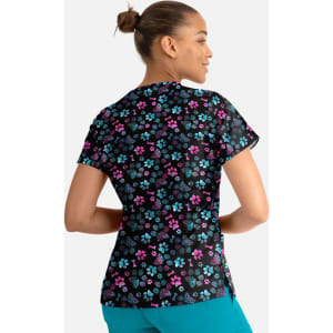 A women's V-neck top featuring a vibrant floral print in pink, blue, and green on a black background, with a logo.