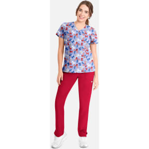 A floral V-neck print top in blue, paired with red pants, worn by a model standing against a plain background.