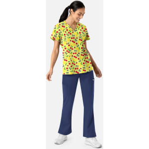 A woman in a yellow patterned V-neck print top and navy trousers, featuring a logo.