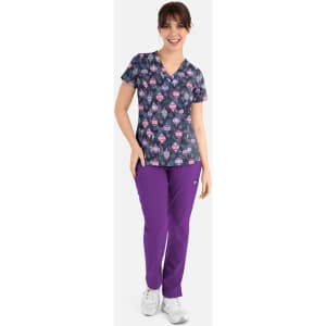 A woman wearing a navy V-neck printed top featuring colourful designs, paired with purple trousers. The outfit has a logo.