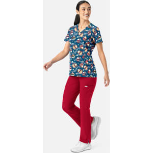 A woman wearing a patterned navy V-neck print top with colourful designs, paired with red trousers and white shoes.