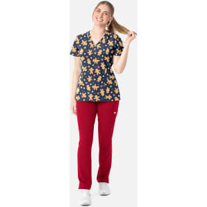 A women's V-neck top with a navy background and gingerbread man print, paired with red pants.