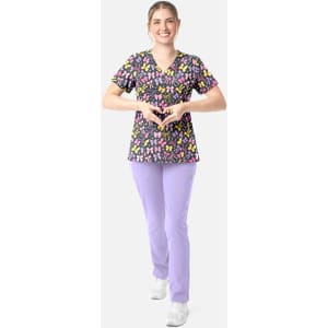 A woman in a black V-neck top with a colourful floral print and purple pants, smiling and posing.
