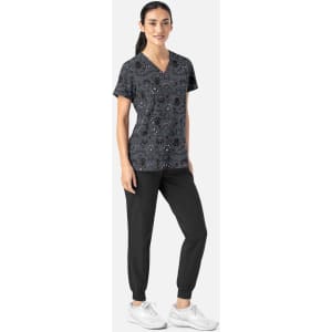A women's black V-neck print top featuring a colourful pattern, paired with black jogger pants and white sneakers.