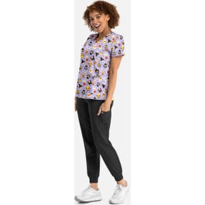 A woman models a purple v-neck print top featuring floral patterns, paired with black joggers and white sneakers.