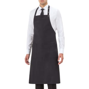 A dark grey apron worn by a model, featuring two front pockets and an adjustable neck strap.