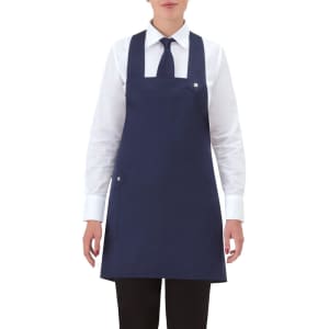 A navy blue apron with a pocket, worn over a white shirt and black trousers, featuring a logo on the apron.