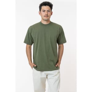 A model wearing a short sleeve, crewneck tee in olive green, featuring a logo on the garment.