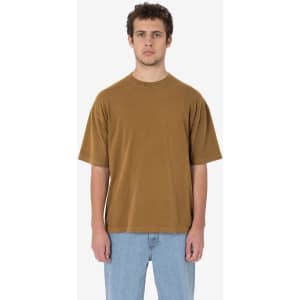 A short sleeve crewneck tee in a rich brown colour, featuring a relaxed fit and a logo. The model has a neutral expression.