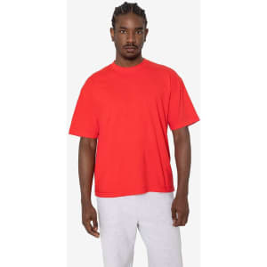 A red short sleeve garment-dyed crewneck tee displayed on a model, paired with grey sweatpants. The tee features a brand logo.