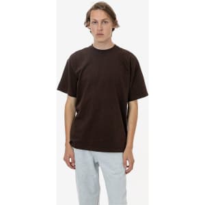 A brown short sleeve crewneck t-shirt with a relaxed fit, paired with grey sweatpants. Features a logo.