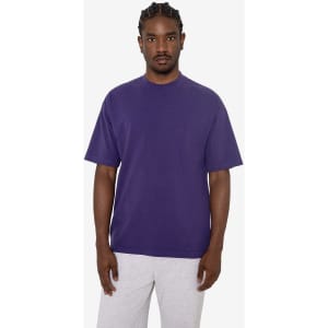 A purple short sleeve crewneck tee displayed on a model, featuring a relaxed fit and no visible logos.