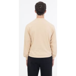 A long sleeve garment dye crewneck tee in a soft beige colour, displayed from the back. Features a subtle logo.