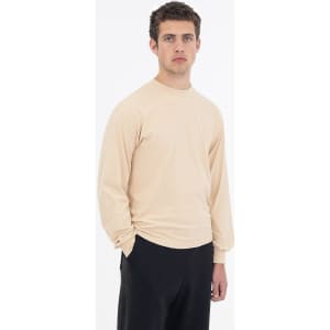 A long sleeve crewneck tee in beige, featuring a fitted design and a logo on the garment.