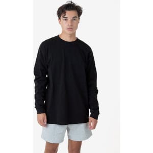 A long sleeve crewneck tee in black, paired with light grey shorts, worn by a model against a plain background.