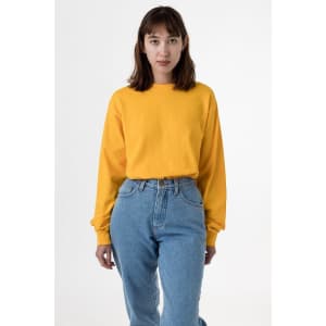 A yellow long sleeve crewneck tee worn with high-waisted blue jeans. The shirt has a logo on it.