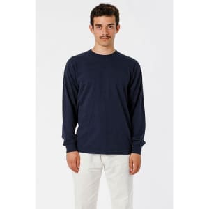 A long sleeve crewneck tee in navy blue, displayed on a model wearing light coloured trousers, featuring a logo.