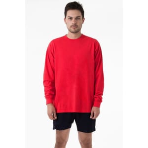 A man wearing a bright red long sleeve crewneck tee, paired with dark shorts, standing against a plain background.