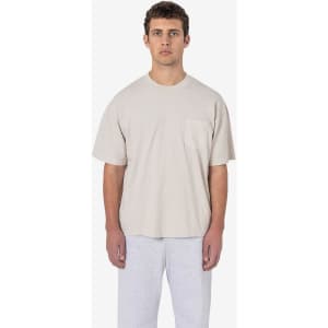 A short sleeve garment-dyed pocket tee in beige, displayed worn by a model with grey sweatpants.