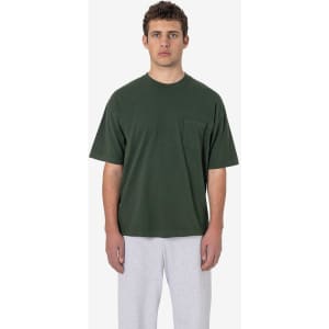 A green short sleeve t-shirt featuring a pocket, worn by a model with grey pants. It has a logo on it.