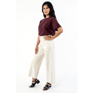 A woman poses wearing a burgundy wide tee and cream-coloured wide-leg trousers, paired with black sandals.