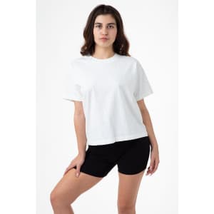 A model wearing a white wide tee shirt paired with black shorts, standing against a plain background.