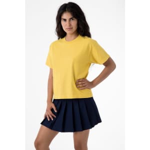 A woman stands wearing a yellow garment dye wide tee and a navy pleated skirt, showcasing the shirt's relaxed fit.