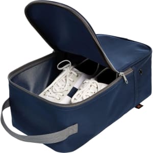 A navy shoe bag with a zippered opening, containing a pair of white sneakers and a handle for easy carrying.