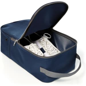 A navy shoe bag with a zippered closure, featuring a handle and storing a pair of white shoes inside.