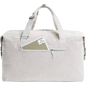 A beige duffle bag with handles, featuring a front zip pocket and a card peeking out. The bag has a logo.