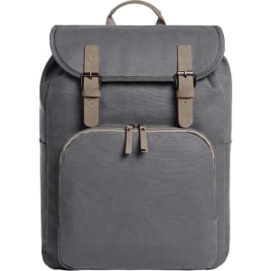 A grey backpack with a flap closure, featuring two buckles and a front zip pocket. It includes a logo on the front.