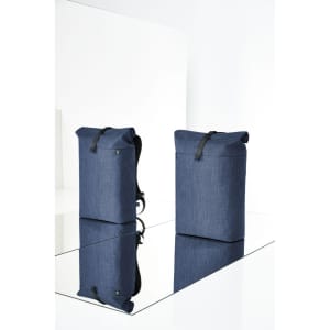 A blue roller backpack with a sleek design, featuring a logo, stands upright on a reflective surface.