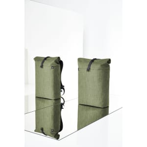 Two olive green backpacks with roll-top closures and black straps, displayed against a reflective surface. Each bag has a logo.