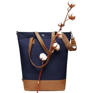 A navy tote bag with a tan base and long straps, featuring a decorative branch with cotton flowers.
