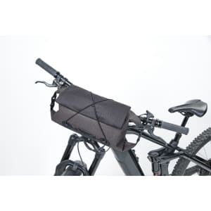A black bicycle handlebar bag secured to a bike's handlebars, featuring a sleek design and straps for attachment.