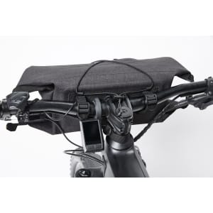 A grey bicycle handlebar bag rests on the handlebars, with a device attached and a logo visible.