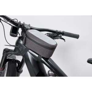 A grey bicycle frame bag sits atop a black bicycle frame, featuring a zip closure and a compact design.