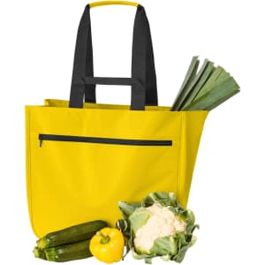 A bright yellow tote bag with black straps, alongside fresh vegetables including leeks, zucchini, cauliflower, and a yellow capsicum.