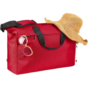 A red duffle bag with black straps, featuring a pair of sunglasses and a straw hat resting on top.