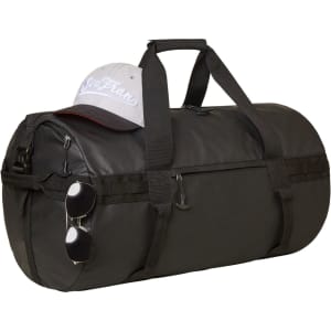 A black duffle bag rests on a surface, topped with a grey cap and a pair of sunglasses hanging from its side.