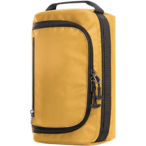 An active wash bag in mustard yellow with a zippered front pocket and a sturdy handle on top.
