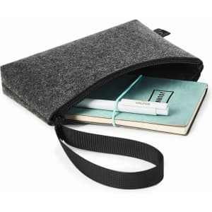 A grey felt zipper bag contains a notebook and a pen, featuring a wrist strap for easy carrying.