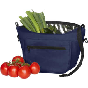 A navy lunch bag with a silver lining, filled with vegetables and a cluster of red tomatoes beside it.